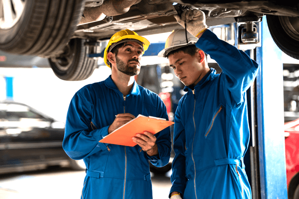 Two professional look technician inspecting car underbody and suspension system